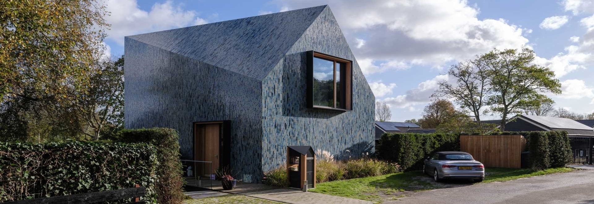 Blue Tiles Cover The Exterior Of This House With A Twisted Roof