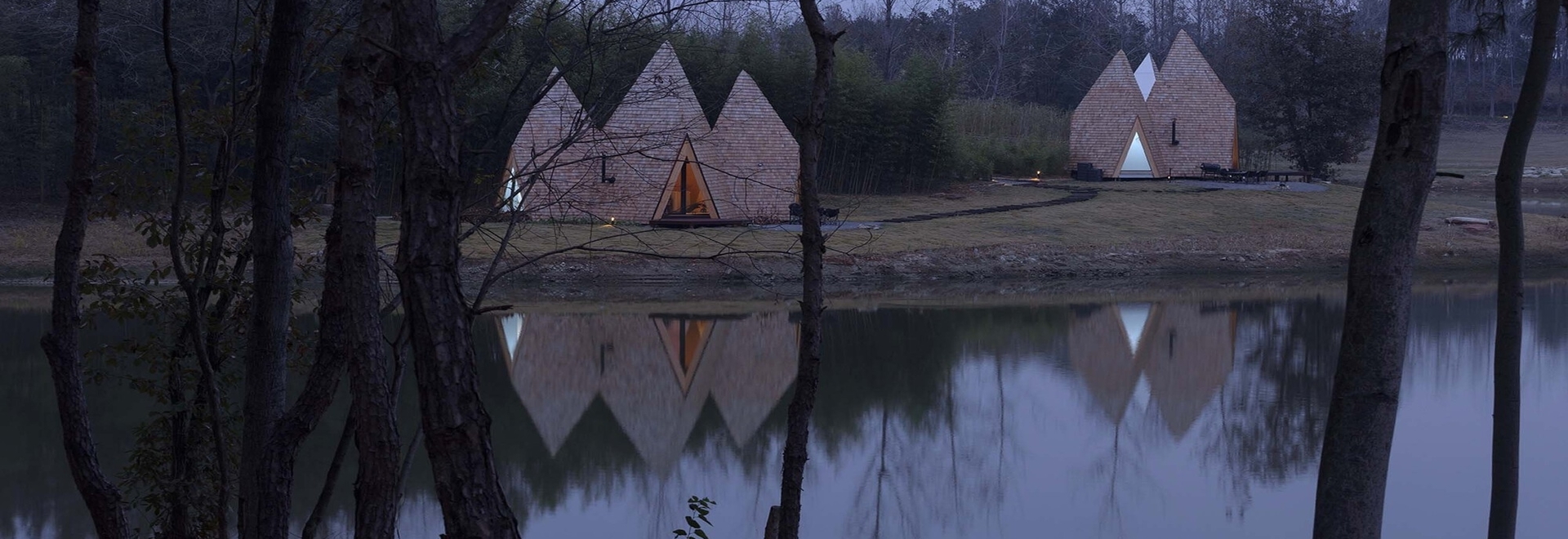 Wooden shingles overlay cluster of monolithic cabins on chinese waterfront