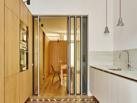 Built Architecture uses oak cabinetry to reorganise a mosaic-floored Barcelona apartment