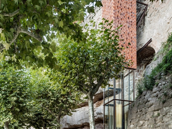 Perforated brick elevator by Carles Enrich connects medieval Spanish town to riverside