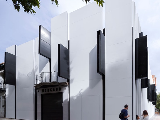 Smaller black panels are irregularly interjected outwards from the facade's 'ribs' and support the building's exterior lighting