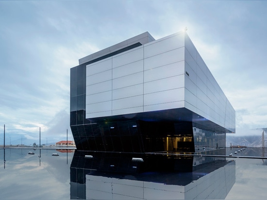 the water’s reflective surface, mirrors the suspended monolithic volume