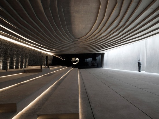 Terraced landscaping surrounds concrete and stone structure of Emre Arolat's Sancaklar Mosque