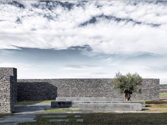 Terraced landscaping surrounds concrete and stone structure of Emre Arolat's Sancaklar Mosque