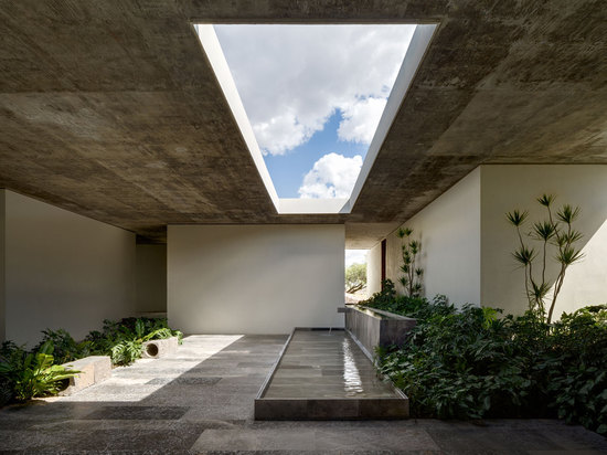 The monolithic roof slab breaks open in the central courtyard, with a large rectilinear skylight streaming daylight down to the reflective pool below