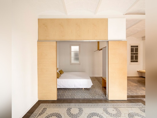 Sliding chipboard units create multifunctional space in Madrid apartment