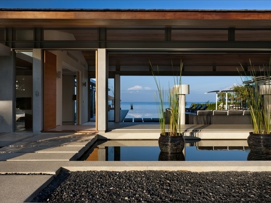 view of the entrance at dusk with the pool and ocean