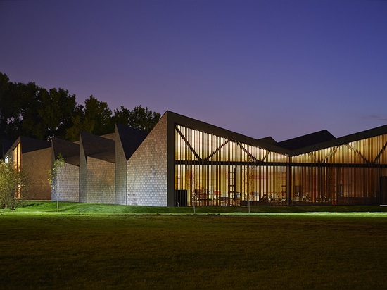 With structural truss shapes alternating between an inverted “V” and an “M”, the roof achieves a rhythmic modulation that allows southern light into the building’s upper clerestory.