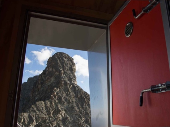 A bivouac is lightly perched on a rocky peak of the Italian Alps