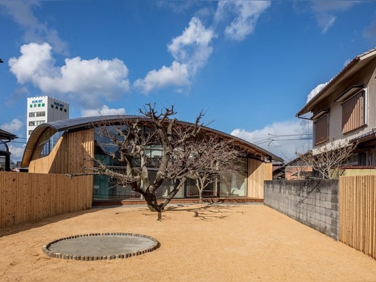 curved wood lattice roof hangs above nasca's blue sky nursery school in japan