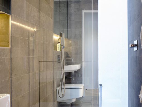 Hard, polished surfaces continue inside the three ensuite bathrooms, which showcase floor to ceiling natural grey stone tiles and wall mounted mirrored cupboards