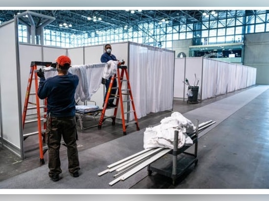 View of construction workers setting up the temporary hospital wards inside the Javits Center.