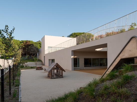 Circular holes connect playgrounds on two levels of a Lisbon school