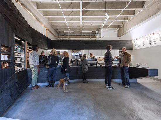 Existing concrete and piping were left exposed and the exterior was clad in scorched wood, which fades into the wood's natural color towards the top part of the facade above the opening.