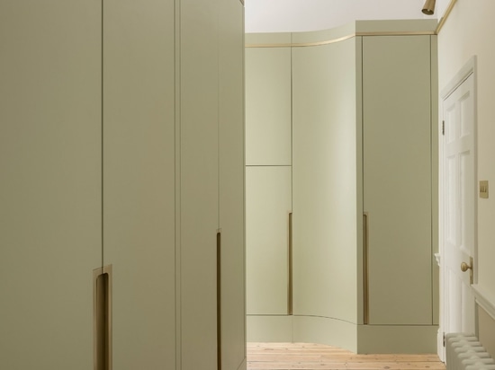 A small antechamber features pistachio-green storage walls