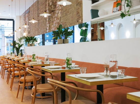 A burnt-orange seating banquette is set against an exposed-brick wall