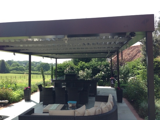 Outdoor living room with bioclimatic pergola  in a country house in England