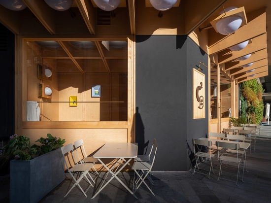 Outdoor seating is sheltered by an overhanging wooden roof