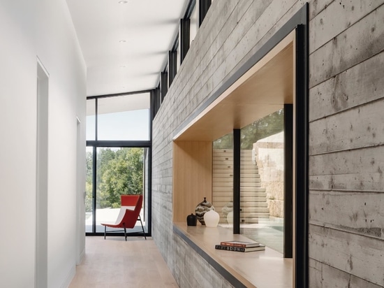 A hallway connecting the two living rooms provides a close-up look at the board-formed concrete wall and access to the bedrooms and bathrooms.