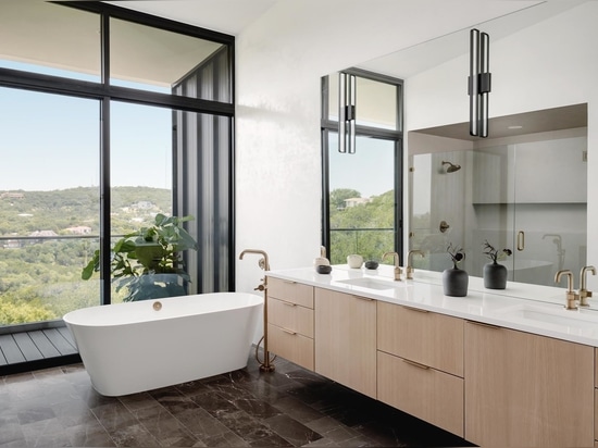 In one of the bathrooms, a mirror reflects the light and view seen through the large windows.