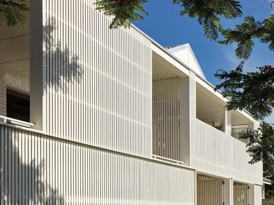 A screen of vertical timber battens visually and climatically shields the existing house.