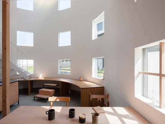 A staircase lands on a desk inside House in Hikone by Tato Architects