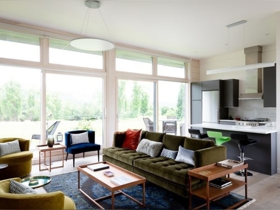 In contrast with whitewashed log surfaces, the interior walls are made of painted gypsum. The wood stove flanked with bookshelves anchors the living room side opposite the kitchen. Photo by Lisa Vo...