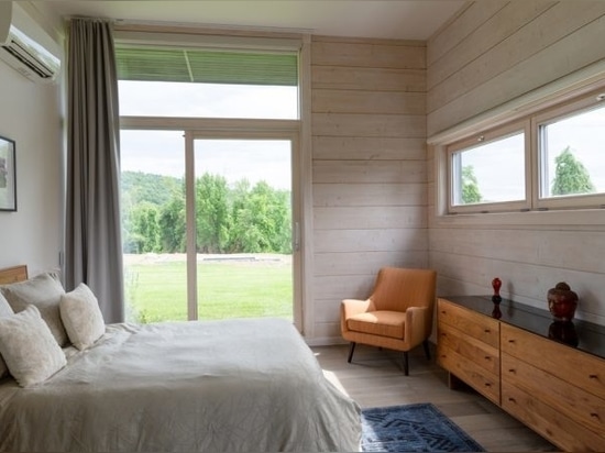 The whitewashed log walls define the perimeter of the building. The windows function in specific ways, balancing the need for privacy and connection to the outdoors in front of the bedrooms. Photo ...