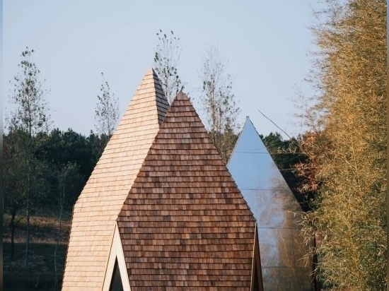 the two geometric structures shape three peaked volumes each covering them in wooden shingles