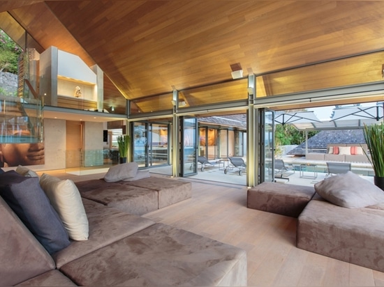 the living room and pool area are subtly connected by the floor-to-ceiling windows