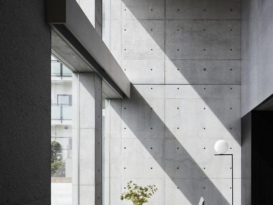 Dynamic curtain of concrete walls of varying heights engulfs japanese home in tranquility