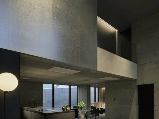 Dynamic curtain of concrete walls of varying heights engulfs japanese home in tranquility