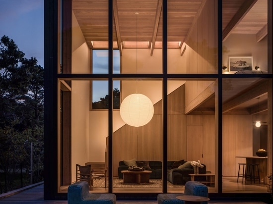 A spherical paper lantern glows through the huge windows at night