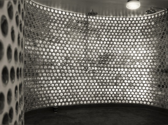 the curved wall of the shower uses glass bottles as a sustainable decision to let light in