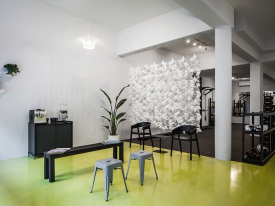 Custom made room divider screen Facet in white, creating a semi-transparent separation between the leisure area and workout space in Workoutclub Rotterdam