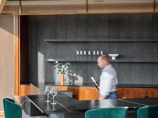 Decorative woven wire mesh installed in corporate interior design as a gantry over a bar