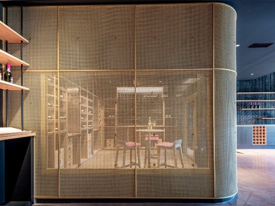 A contemporary wine tasting space features M22-83 brass woven wire mesh as a space divider for a tasting room.