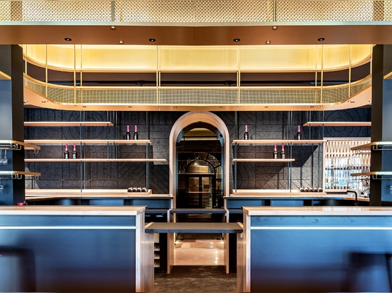 A contemporary wine tasting space features M22-83 brass woven wire mesh as a ceiling gantry that forms a sculptural canopy above the bar.
