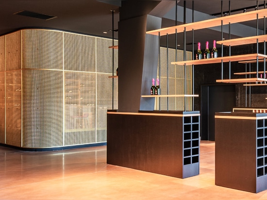 A contemporary wine tasting space features M22-83 brass woven wire mesh as a space divider for a tasting room.